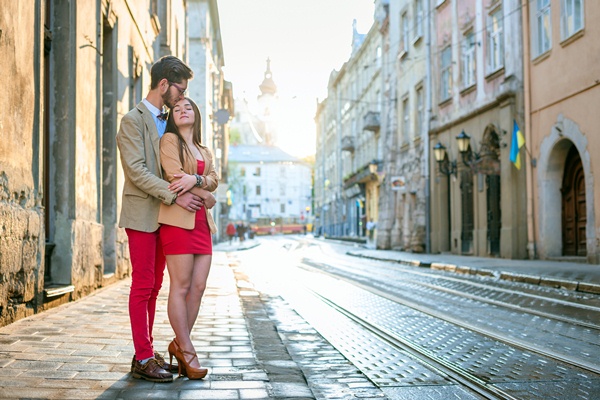Young fashion elegant stylish couple posing on streets of european city in summer