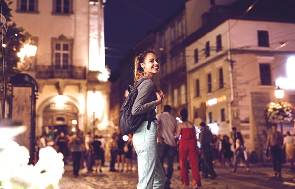 young woman tourist walking on the night street in historic part of city, Ukraine, Lviv.